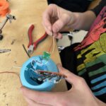 „Kinder lötet elektronische Bauteile in der Technikwerkstatt Kempodium und baut eine LED‑Nachtlicht mit blauen 3D Gehäuse.“