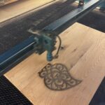 Laser-Cutter graviert ein Ornament in eine Holzplatte in der Technikwerkstatt des Kempodium in Kempten